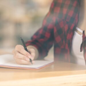 vrouw die in een notitieboekje schrijft om zich voor te bereiden op stoppen met roken