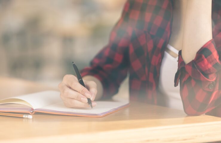 vrouw die in een notitieboekje schrijft om zich voor te bereiden op stoppen met roken