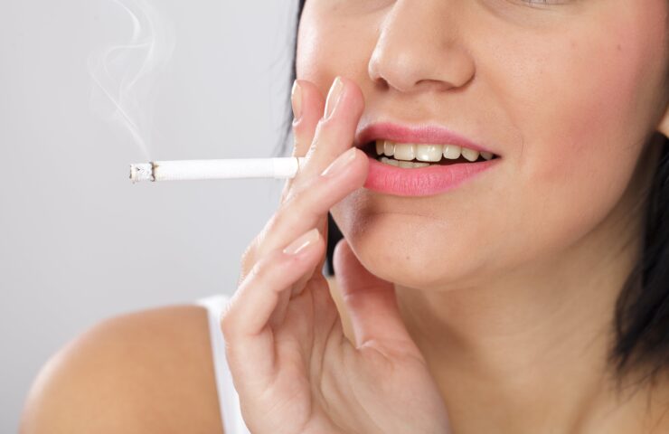 Vrouw rookt een sigaret, wat leidt tot een slechtere mondgezondheid